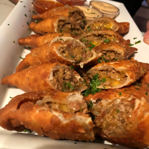 A platter of golden-brown, crispy empanadas filled with meat and cheese, garnished with parsley.
