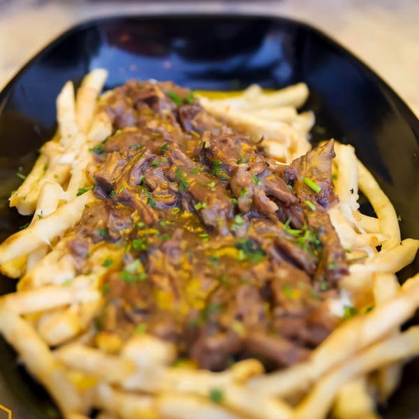 A close-up of The Hive Bar & Bistro's poutine, featuring fries topped with gravy and cheese curds.